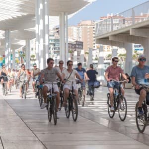 Landausfluggäste fahren entlang der modernen Hafenpromenade Málagas