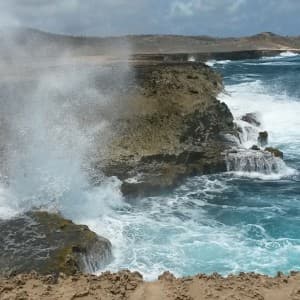 Wellen peitschen an die raue Küste von Aruba