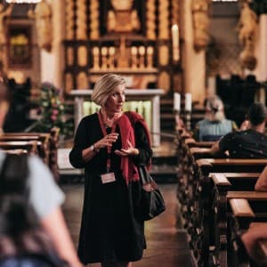 Eine Reiseleiterin steht in einer Kirche und erzählt etwas