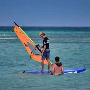 Ein Lehrer gibt einem Jungen Anweisungen zum Windsurfen