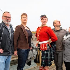 Vier Touristen posieren mit einem Darsteller in traditioneller Uniform in Citadel Hill
