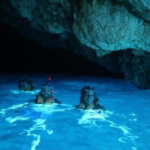 Shore excursionists bathing in the blue water of the cave